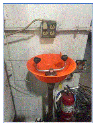 Workplace eyewash station – next to a live electrical outlet & an expired fire extinguisher.